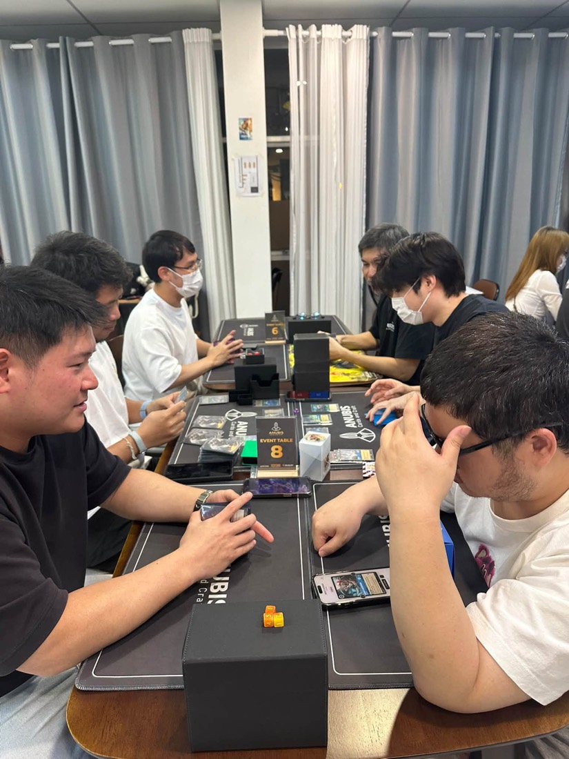 A long table of players mid-game at Anubis Cards and Craft