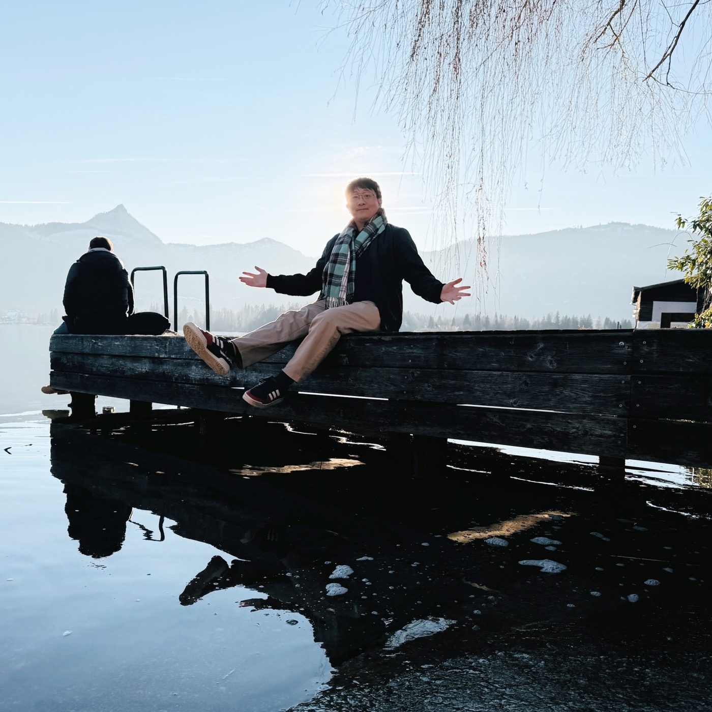 Philly sitting on a wooden pier over a still mountain lake