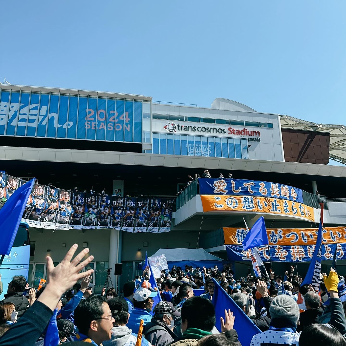 Supporters in blue waving flags outside a stadium on matchday