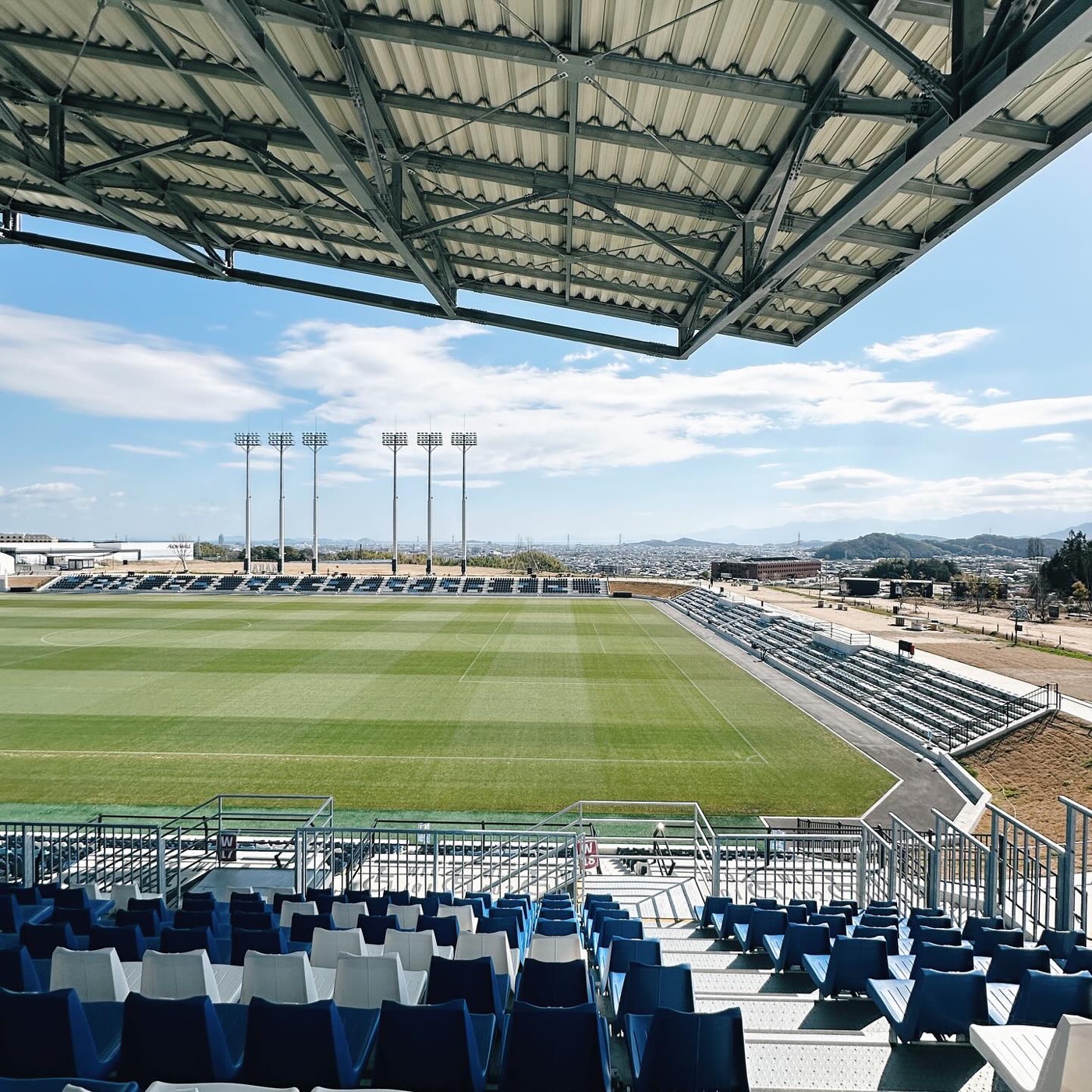 Empty stadium stands and a green pitch under a blue sky, Japan